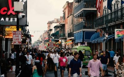 Bustling street scene in the New Orleans French Quarter filled with tourists and local shops.